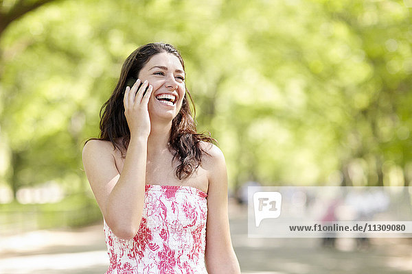 Lachende Frau  die über ein Mobiltelefon spricht