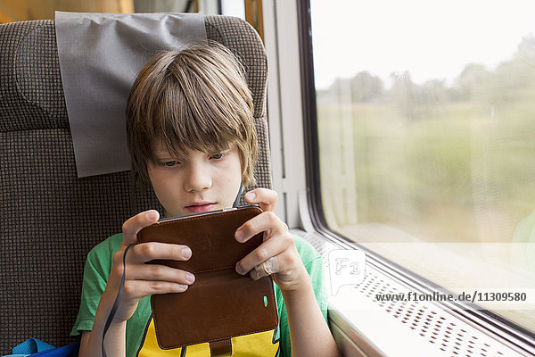 Junge im Zug mit Mobiltelefon