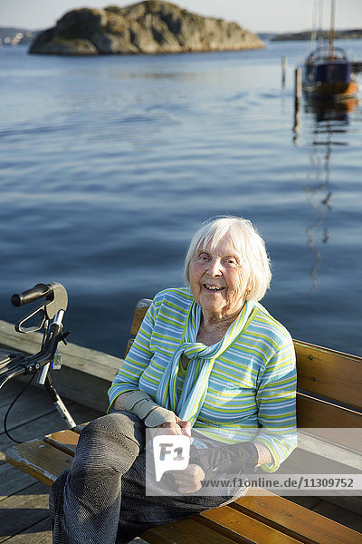 Lächelnde ältere Frau am Meer sitzend