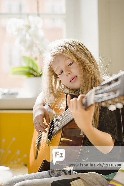 Girl playing guitar in bedroom