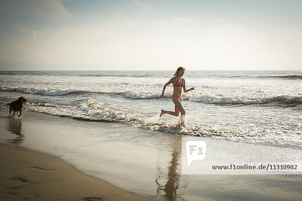 Mexico  Riviera Nayarit  Woman running with dog at the beach