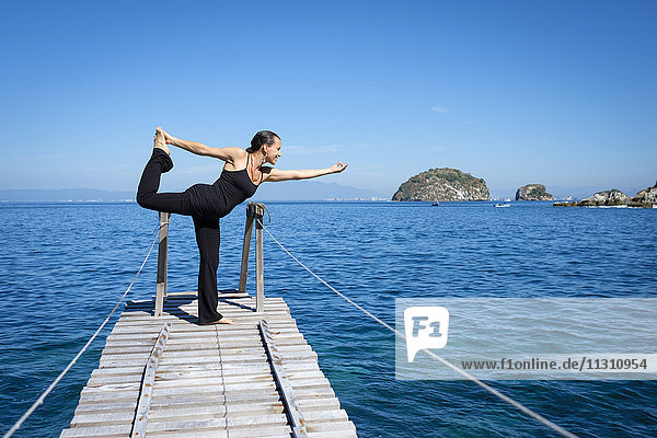 Frau praktiziert Yoga auf einem kleinen Dock an der Cean.