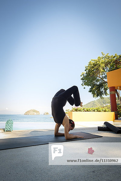 Frau  die Yoga am Meer praktiziert