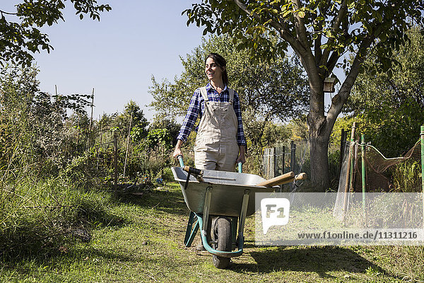 Woman working on farm pushing wheel barrow