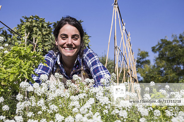 Happy woman working on farm  examining flowers