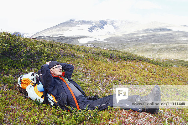 Mann liegt auf einem Hügel und betrachtet die Landschaft