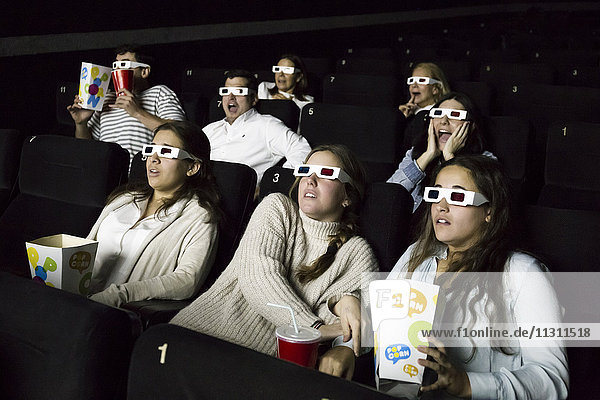 Erschrockene Leute mit 3D-Brillen  die einen Film in einem Kino sehen.