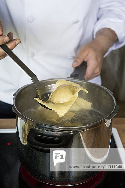 Man cooking raviolis in a pot in a kitchen