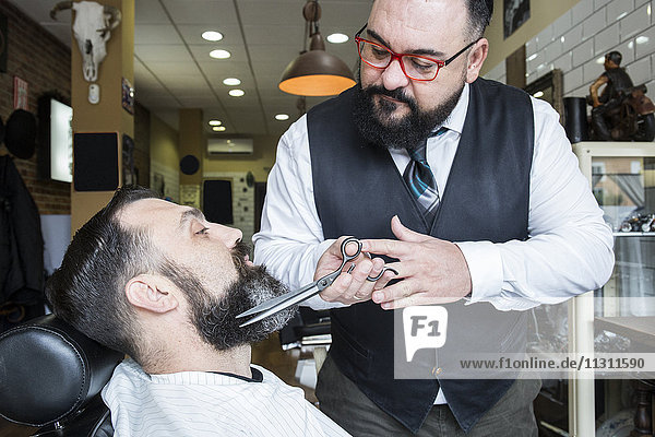 Barber cutting man's beard