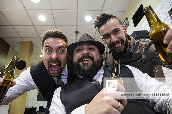 Männer mit Bier lachen vor der Kamera im Friseursalon