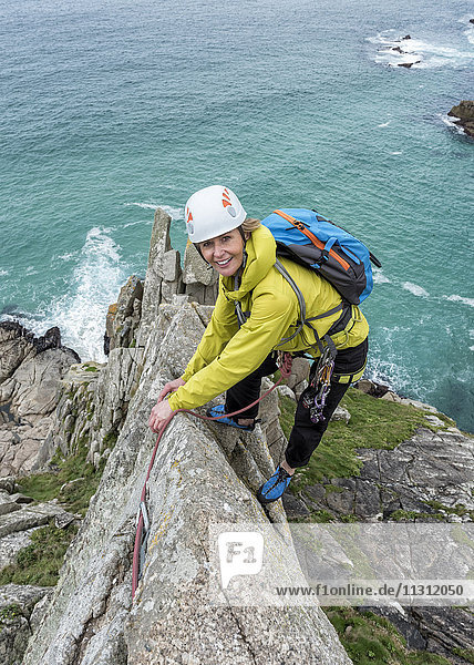 UK  Cornwall  smiling woman climbing on Commando Ridge