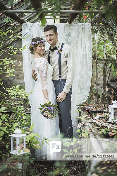 Bride and groom embracing in greenhouse