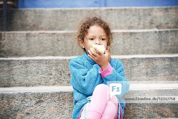 Girl sitting on steps and eating apple