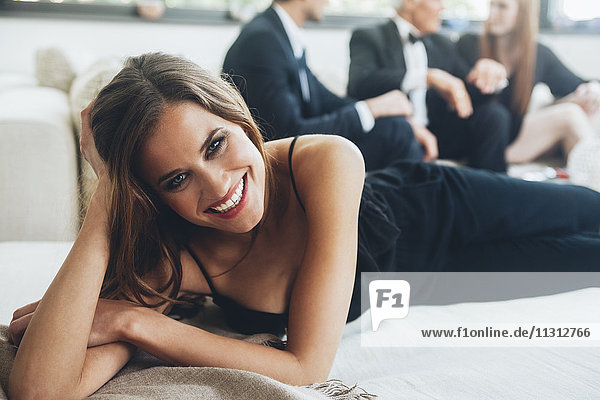 Beautiful woman lying on couch  party guests in background