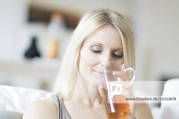 Blonde Frau genießt ein Glas Tee