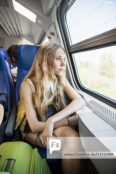 Junge Frau schaut durch ein Fenster im Zug