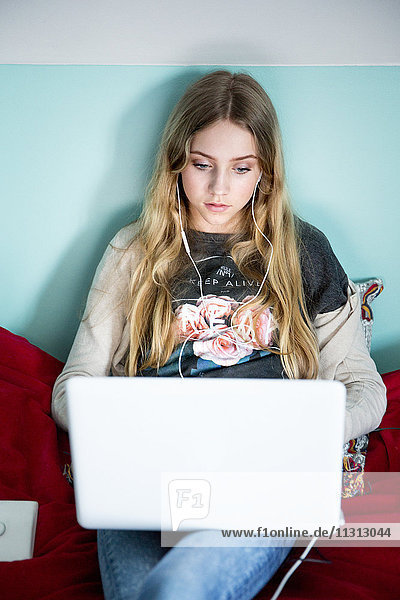 Junge Frau mit Laptop auf dem Bett