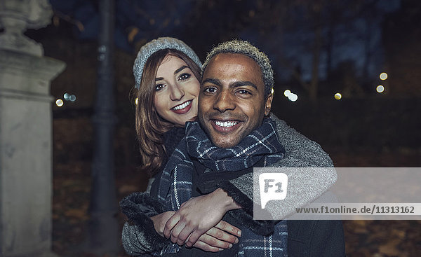 Portrait of happy young couple in front of park