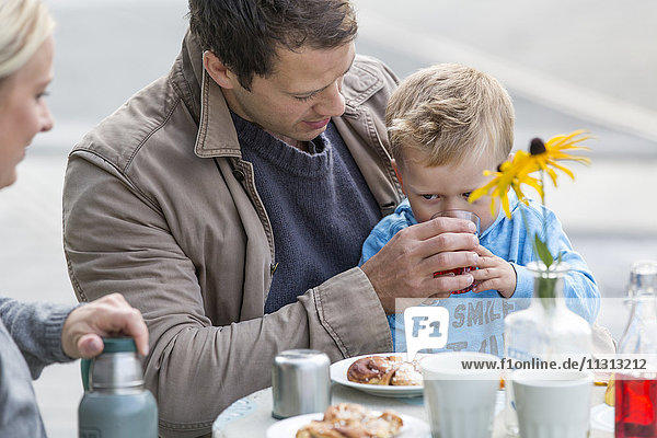 Eltern mit Sohn essen Kuchen in einem Straßencafé