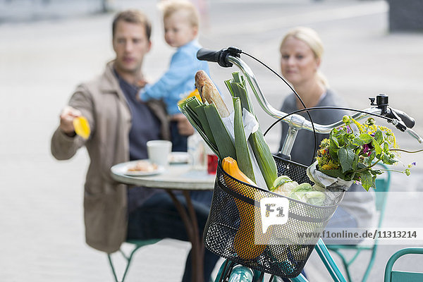 Lebensmittel im Fahrradkorb und Familie im Hintergrund