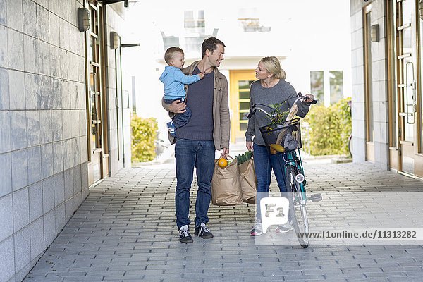 Eltern mit kleinem Jungen beim Spaziergang nach dem Einkaufen