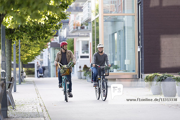 Couple cycling on sidewalk