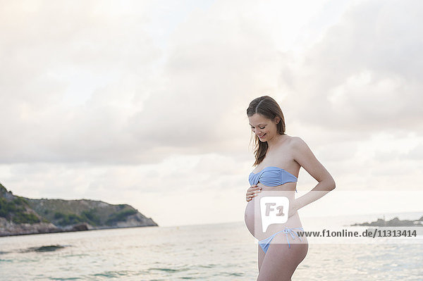 Schwangere Frau am Strand stehend