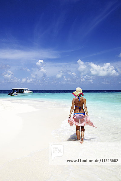 Maldives  woman walking on sand beach