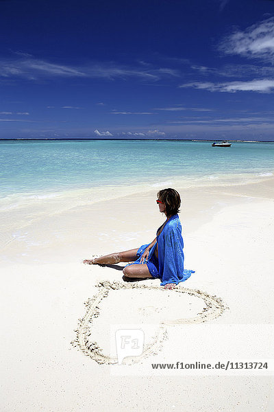 Maldives  woman sitting on beach at shallow water