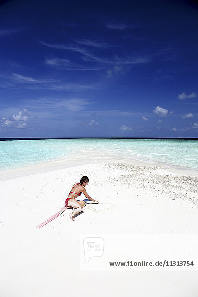 Malediven  Frau am Strand im flachen Wasser