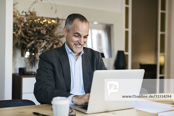 Successful businessman sitting at desk  working om laptop