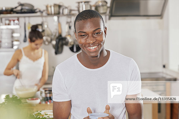 Portrait eines glücklichen jungen Mannes mit Kaffeetasse in der Küche