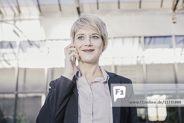 Porträt einer lächelnden blonden Geschäftsfrau am Telefon