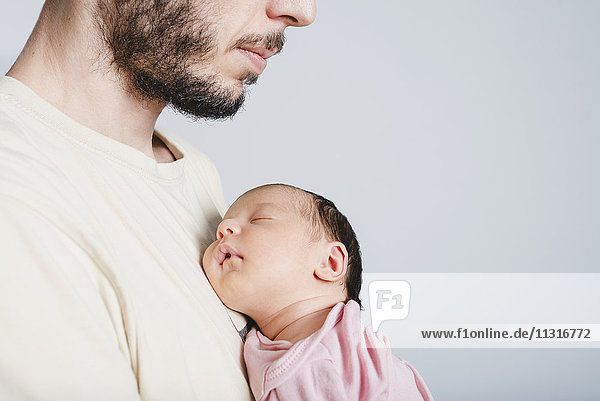 Vater hält schlafendes Neugeborenes Mädchen in der Hand
