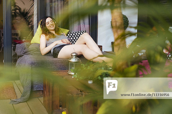 Entspannte junge Frau beim Musikhören auf der Terrasse