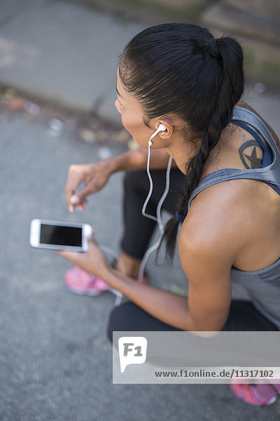 Female athlete listening to music with smartphone