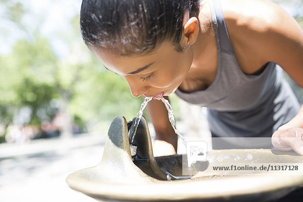 Female athlete drinking water from well
