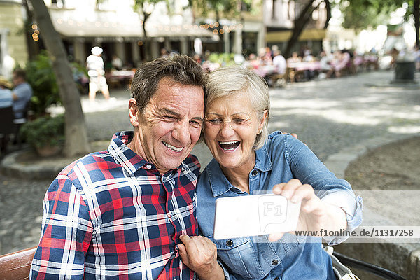 Lachendes Seniorenpaar nimmt Selfie mit Smartphone