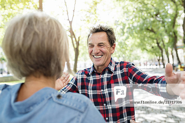 Porträt eines glücklichen älteren Mannes  der eine ältere Frau begrüßt.