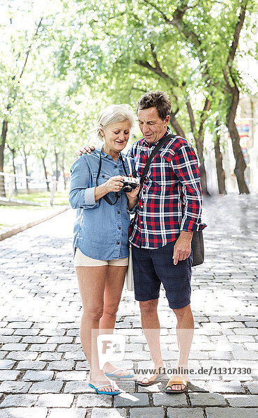 Seniorenpaar in Shorts und Flip-Flops mit Blick auf die Kamera