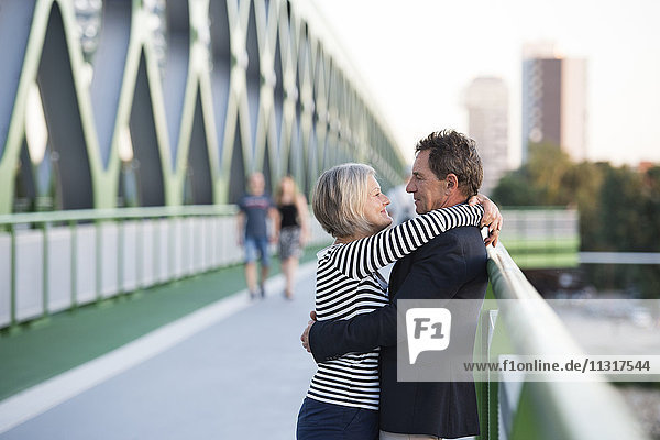 Seniorenpaar umarmt auf einer Brücke
