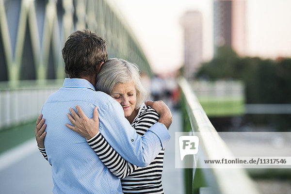 Seniorenpaar umarmt auf einer Brücke