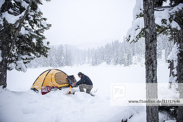 Senior man camping in snow-covered landscape