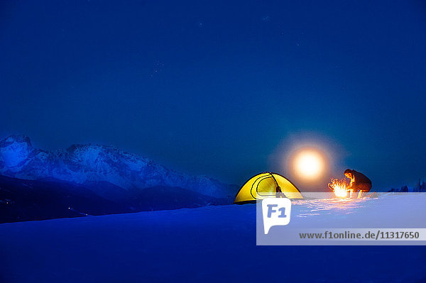 Seniorencamping in verschneiter Landschaft bei Vollmond