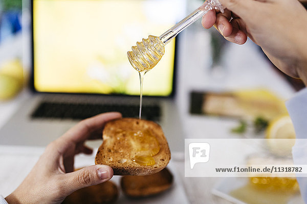 Woman dripping honey on toast at home  close-up
