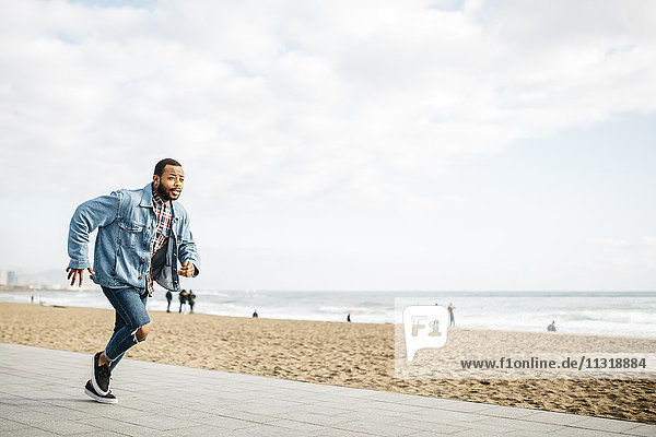 Young man running on beach promenade