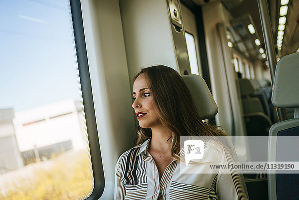 Frau im Zug mit Blick aus dem Fenster