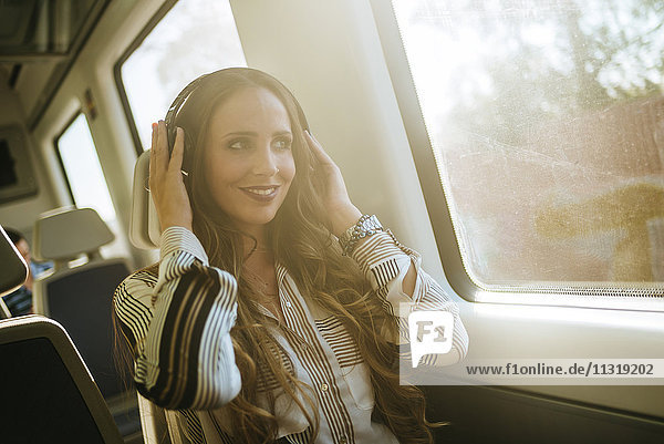 Frau im Zug beim Musikhören mit Kopfhörern