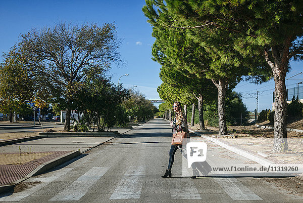 Frau mit Koffer überquert Straße