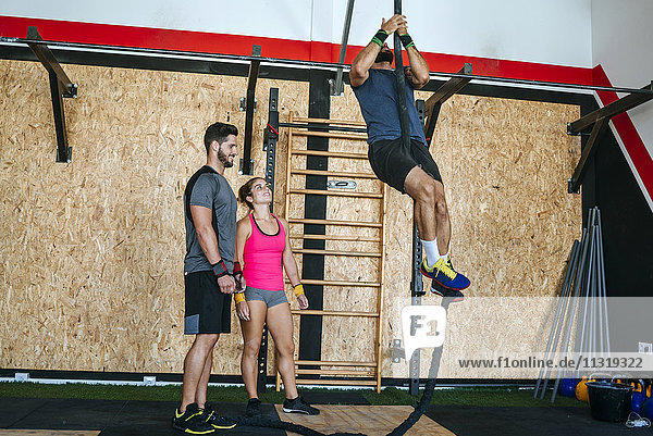 Athletes climbing a rope in gym